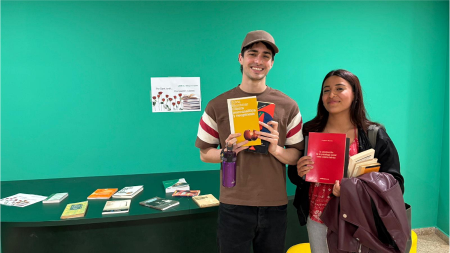 Dos alumnes agafant llibres a la paradeta de la facultat